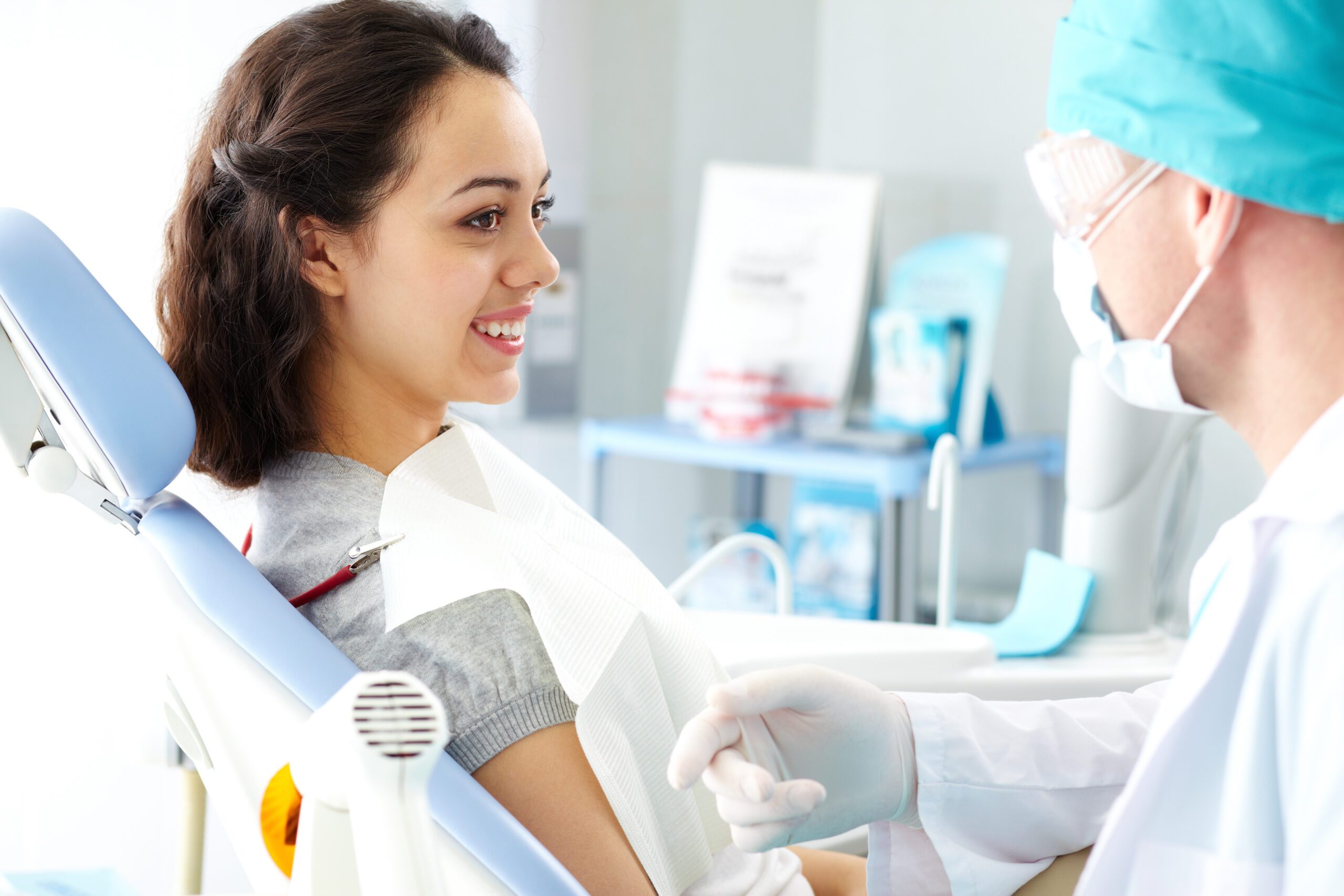 Young female patient looking at dentist while he describing the process of dental treatment