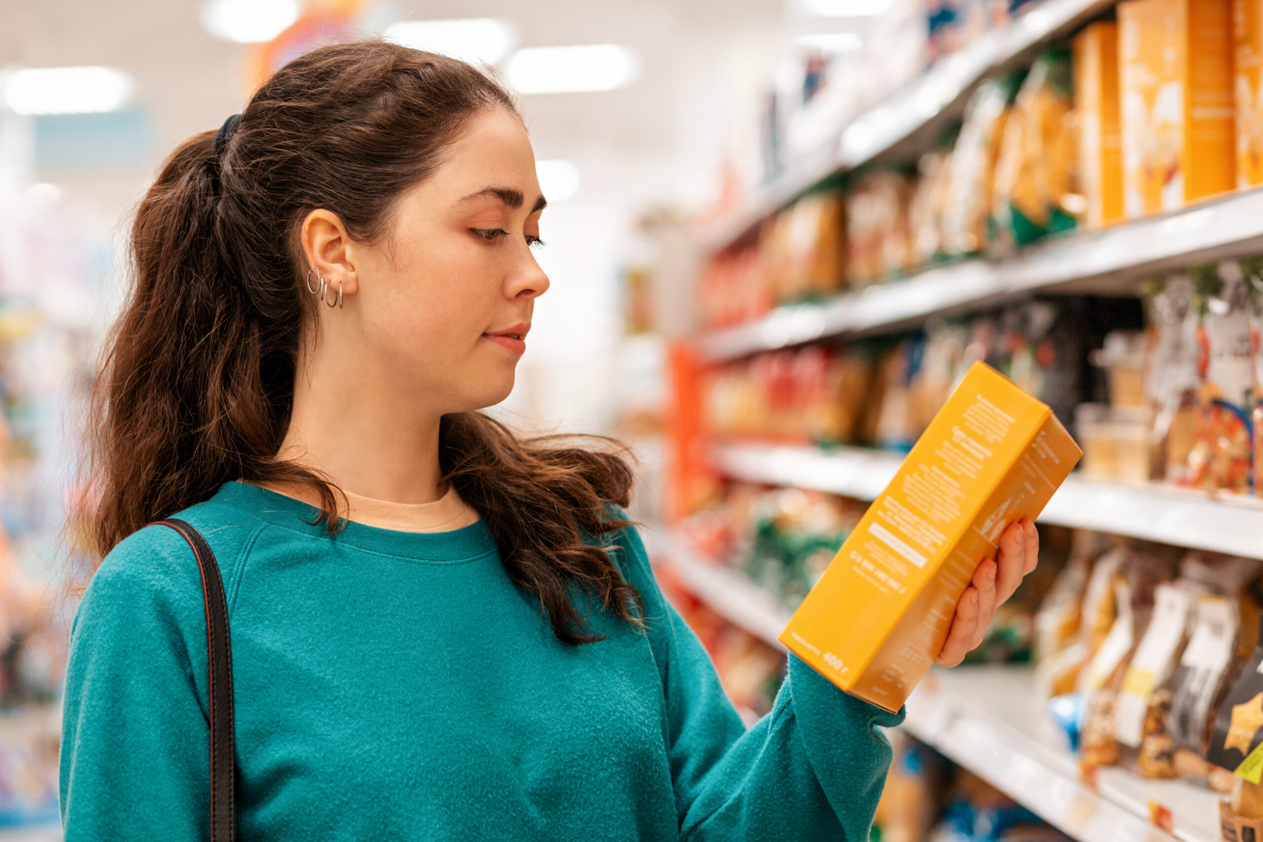 Portrait of a young Caucasian beautiful woman who reads the ingredients on the product packaging. Shelves with goods in a blur in the background. The concept of buying goods and shopping. SSUCv3H4sIAAAAAAAACnRSy27EIAy8V+o/RJyLlJBkAz1X/YmqBwPOLloWVoS0qlb77yUPWg7tDY/t8XjM7fGhqoiEySjyXN2WKMXG2nmKAaLxLsH1044HdBpDiaA20QcDtgQlRHVycMEEutnaBb6vSTJFiPOE0zJshxREPCaODfyh2BS9bXGVE2sydaQUefVeV+B09RKMO5OnomKaZa4gGd7G/cP1V/dv5/Z4z/vBEZ36WlcoVgtoEbbVdtXkwITsWqUo67GmXS8aKpAxKmXNGiEBOYx5MmH9oR4boWkztiPt9KgoZxzpOOixE+IgpBarpE0HOX9GDJfSSZi18YWJH16BXQraQuY1GGXcsWjz8bQeNbcpP7sYlv1+bCHW+ytIu1x0TJyY8RNMUyrXGS8GqfSF/KWY43xc3dlZiU6HX8KmZV0r+oGzTjRsGPiwF2yf5WQSzyonE6VYnY0uVzeLAiI4CM07TjnKQ/K7bpPfvKd9O3RtjbUQkiUL798AAAD//wMA7AZDbfYCAAA=